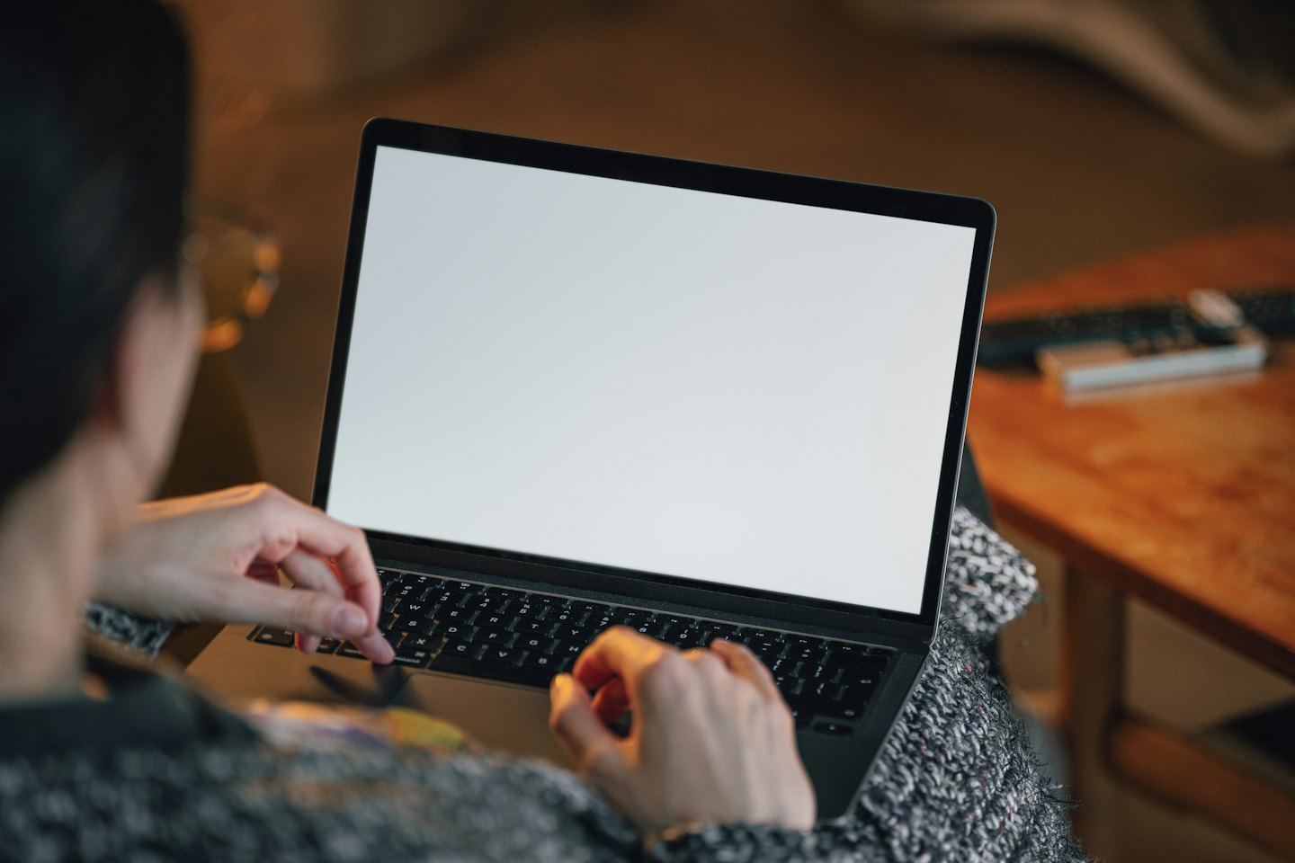 Person typing on a laptop with a blanket on their lap.